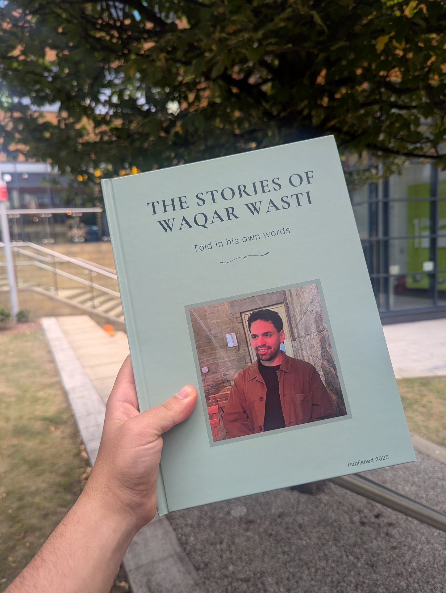 Book titled 'The Stories of Waqar Wasti' held by a person outdoors.