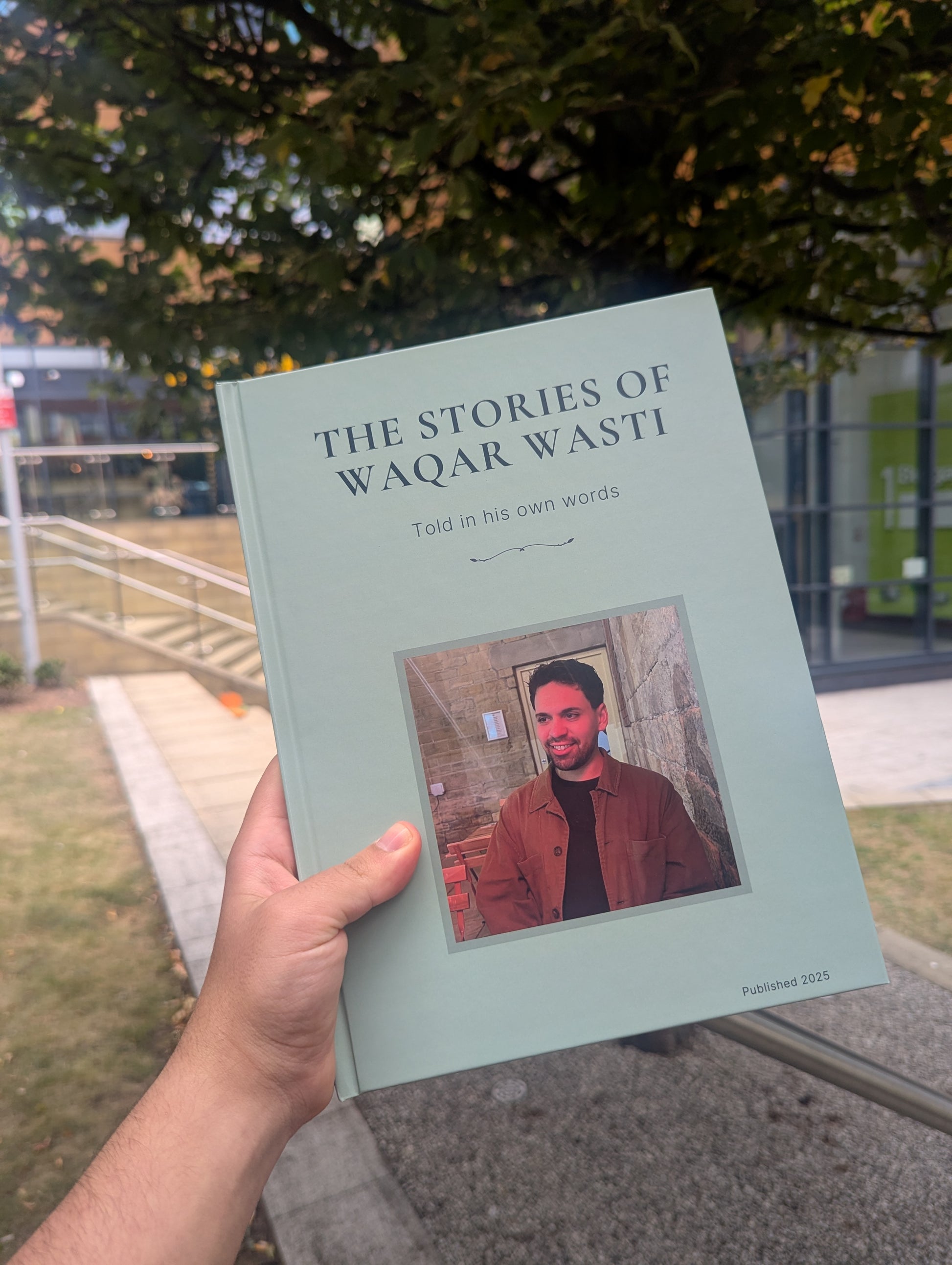 Book titled 'The Stories of Waqar Wasti' held by a person outdoors.